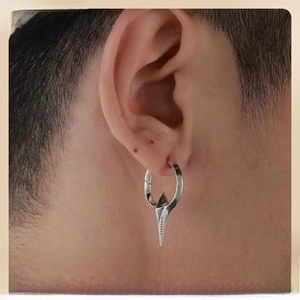 Close-up of a silver punk stud earring featuring a sharp metallic cone spike pendant