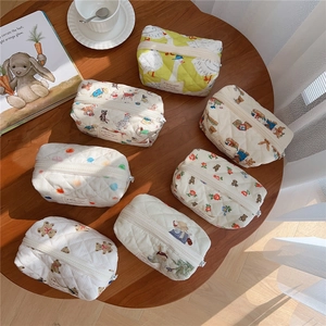 Detailed top view of quilted bear and floral cosmetic bags on a warm wooden table