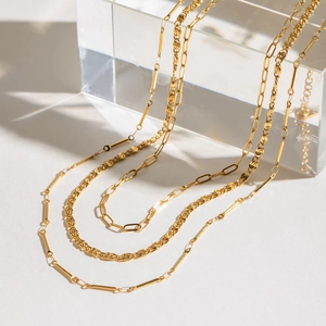 Layered gold stainless steel necklaces with twist and square cable chain designs