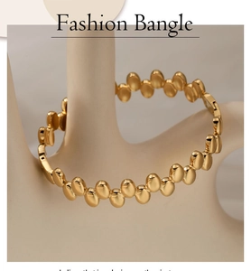 Macro detail of high-shine gold-plated stainless steel polka-dot buckle bangle for women