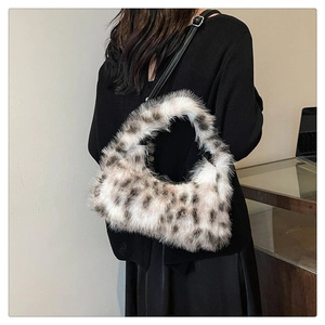 Detail shot of plush leopard print crescent bag with black leather shoulder strap and buckle