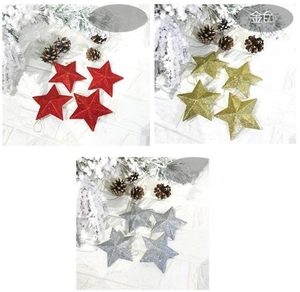 Detail of glittered star Christmas ornaments in red, gold, and silver sets on white wall