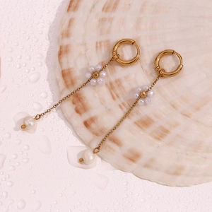 Detail of 18K gold plated hoop earrings with delicate pearl flower tassel on shell
