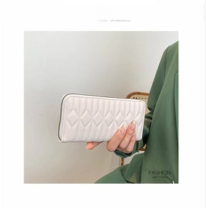Fashionable lady's ivory white quilted wallet held by model in dark green suit