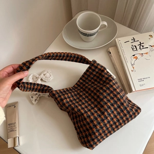 Detail of tweed checkered tote bag with orange and black houndstooth pattern weave