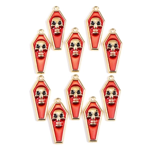 Flat lay of ten red enamel coffin charms with gold skull details for Halloween jewelry