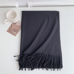 Close-up of a soft black cashmere-style scarf with elegant tassels on a white background