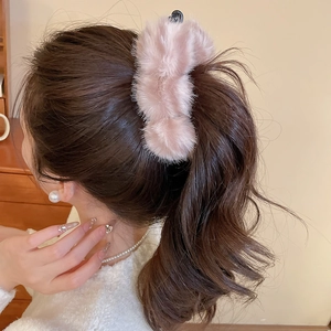 Détail de la pince à cheveux en peluche rose avec texture douce sur coiffure élégante