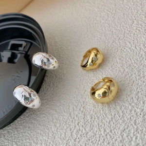 Macro shot of silver and gold earrings with star engravings and zircon stones