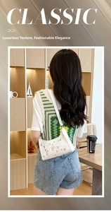 Close-up of white underarm bag with detailed pink floral embroidery and slim shoulder strap