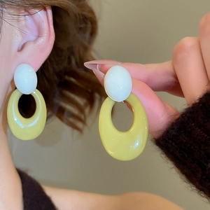 Detail view of oval resin earrings featuring cream and yellow geometric contrast style