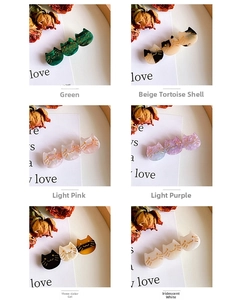 Detailed view of six cat-shaped acetate hair clips in assorted colors and patterns