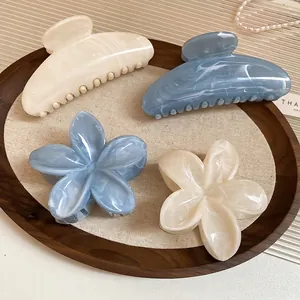 Pinces à cheveux fleurs en acrylique à motif marbré blanc et bleu sur un plateau en bois