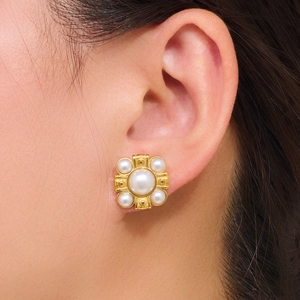 Élégantes boucles d'oreilles en acier doré avec perles et zircons portées par un mannequin