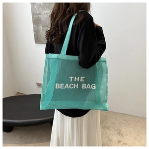 Detail of mint green mesh beach bag with THE BEACH BAG logo shown on model