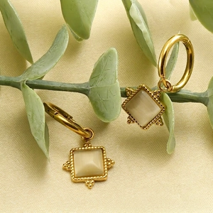 Vintage 18K gold-plated square cat eye stone drop earrings on warm fabric background