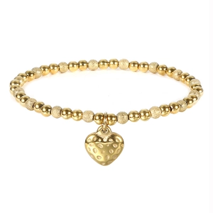 Macro detail of 18K gold beaded elastic bracelet with heart charm and textured sand beads