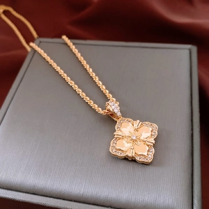 Macro detail of 18K gold flower clover pendant with star relief on jewelry box