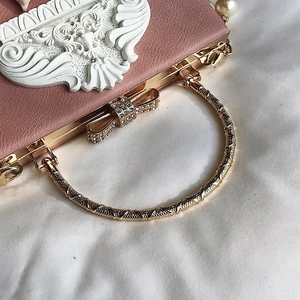 Detailed side view of pink floral embossed evening bag with golden ring handle