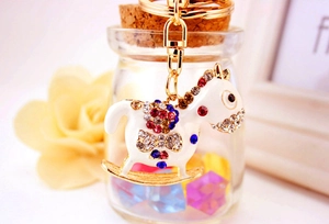 Close-up of a crystal-encrusted rocking horse keychain with colorful rhinestones and gold base
