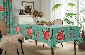 Macro detail of Christmas house and tree pattern on blue cotton linen tablecloth fabric
