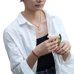 Collier avec pendentif lettre M en acier inoxydable plaqué or 18K et nacre sur un mannequin