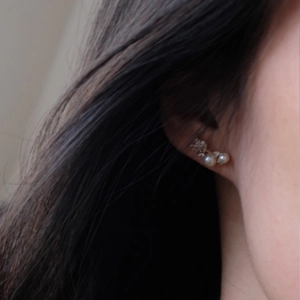 Close-up of pearl earrings with micro-set crystals worn on ear for elegant style