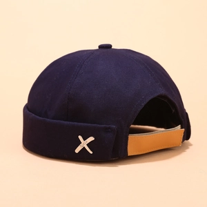 Detail of navy cotton docker hat featuring brown leather strap and silver metal cross accent