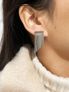 Close-up of elegant silver layered fringe tassel earrings worn on a female model