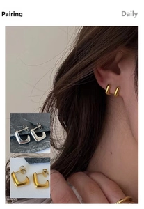 Detail view of U-shaped gold and silver earrings showing texture and model ear styling