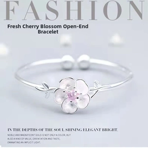 Detailed close-up of a silver cherry blossom cuff bracelet with a pink gemstone center
