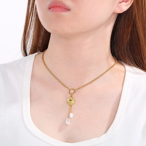 Vue détaillée du collier doré avec médaille soleil et perles pendantes sur la clavicule