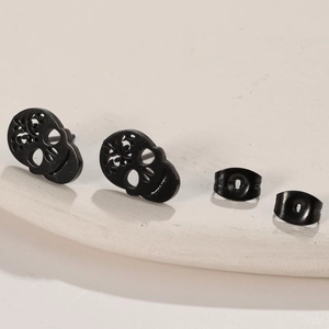 Macro shot of matte black hollow skull stud earrings with butterfly backings