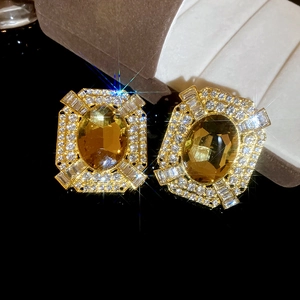 Macro shot of vintage gold earrings with yellow gemstone and sparkling crystal starburst