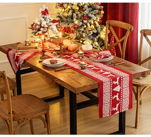 Detail of red Christmas table runner with white reindeer and snowflake patterns on wood table