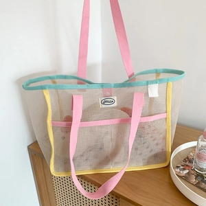 Detail of mesh tote bag with blue trim and pink handles showing breathable net material