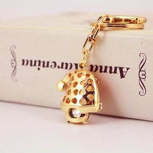 Golden snowman metal keychain featuring rhinestone accents on a vintage book background