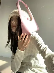 Pink hobo shoulder bag in leather with zipper detail worn by a model in soft daylight