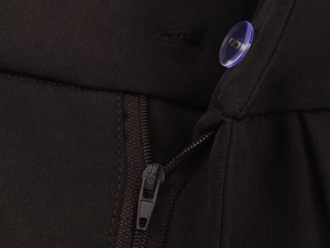 Macro shot of dark twill fabric detail with blue resin button and hidden nylon zipper