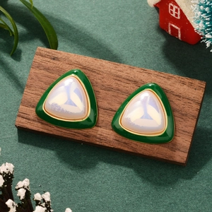 Detail of luxury triangle pearl earrings with green enamel on festive wooden stand
