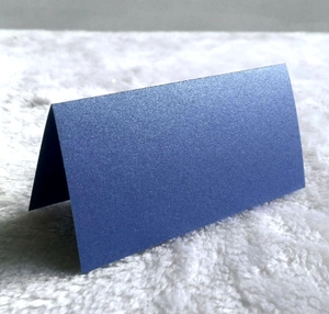 Macro shot showing dark blue pearlescent paper place card on soft white plush surface