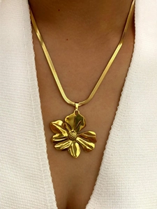 Detailed close-up of a large gold flower pendant on a minimalist snake chain necklace