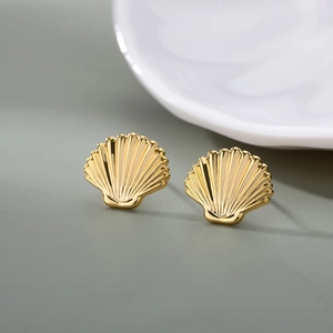 Macro shot of gold shell earrings with detailed radial stripes and minimalist metal texture