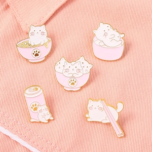 Gros plan de pins en émail chat sur tissu en jean rose avec détails en métal doré