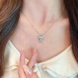 Close-up of silver bow pendant necklace with sparkling rhinestones worn on neck