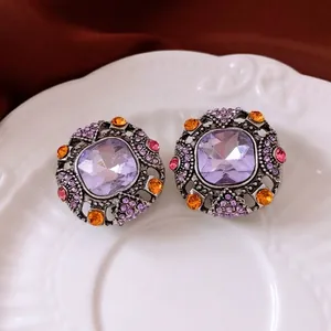 Vintage style square purple stone earrings with colorful crystals on a white ceramic plate