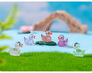 Close-up of mini resin ducks with glitter sequins in a miniature landscape garden