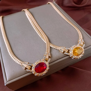 Detailansicht goldener Schlangenkette mit roten und gelben Kristallanhängern im Vintage-Stil