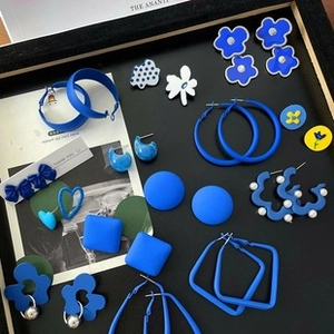 Flat lay of Klein Blue floral, heart and pearl stud earrings on black background