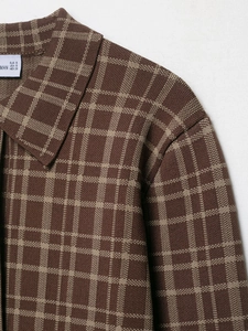 Detailansicht des Karomusters und des quadratischen Ausschnitts der braunen Jacke